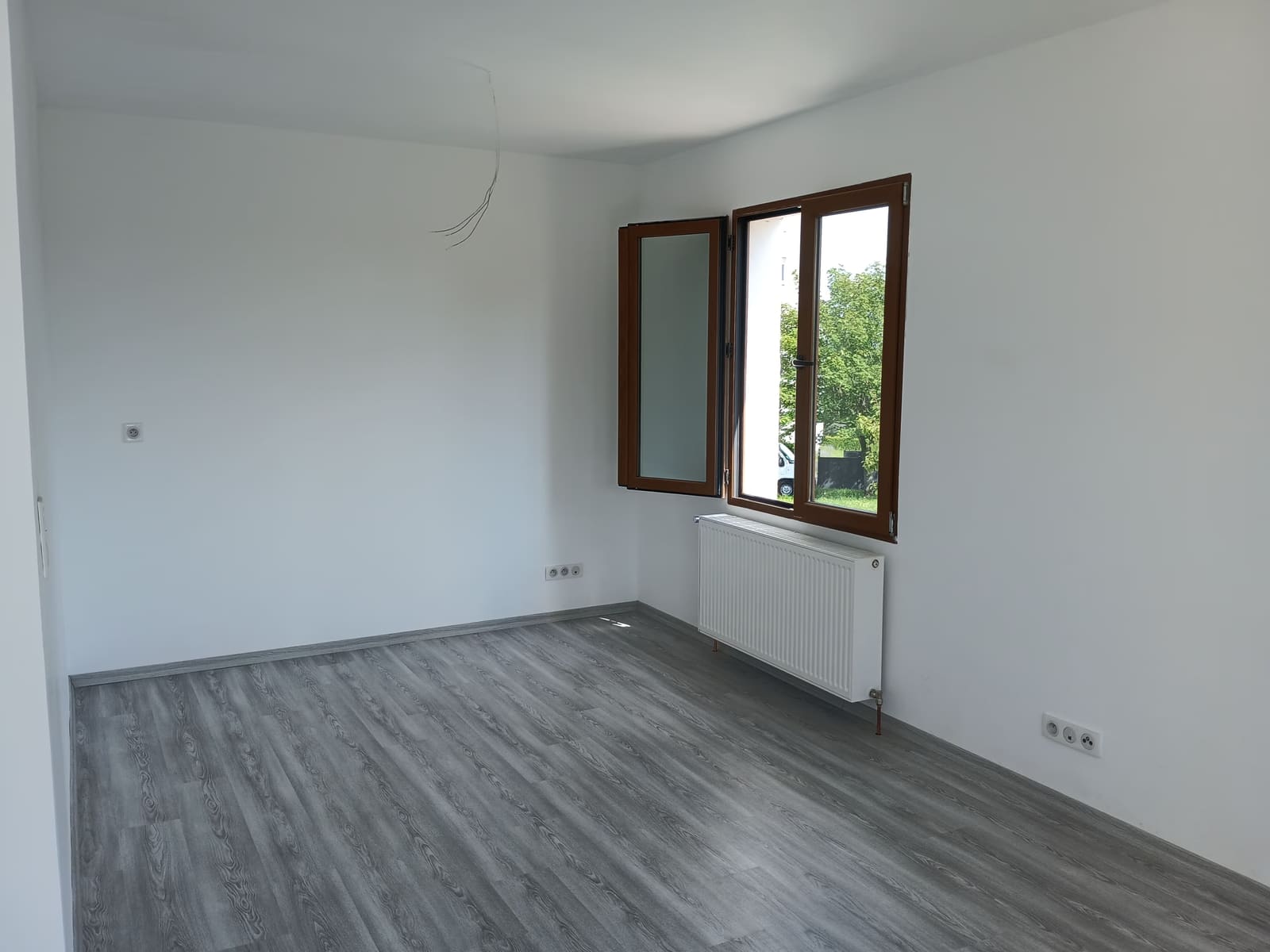Chambre entièrement rénovée avec murs blancs, sol stratifié gris et fenêtre bois à double vitrage