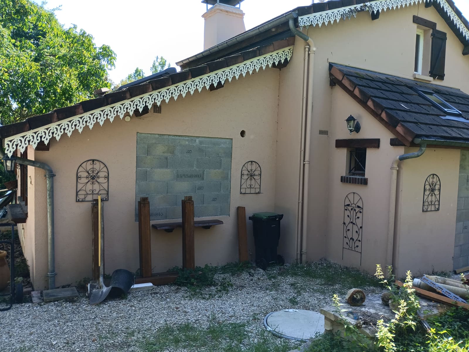 Façade de maison en cours d’habillage, parement pierre posé sous une marquise en tuiles