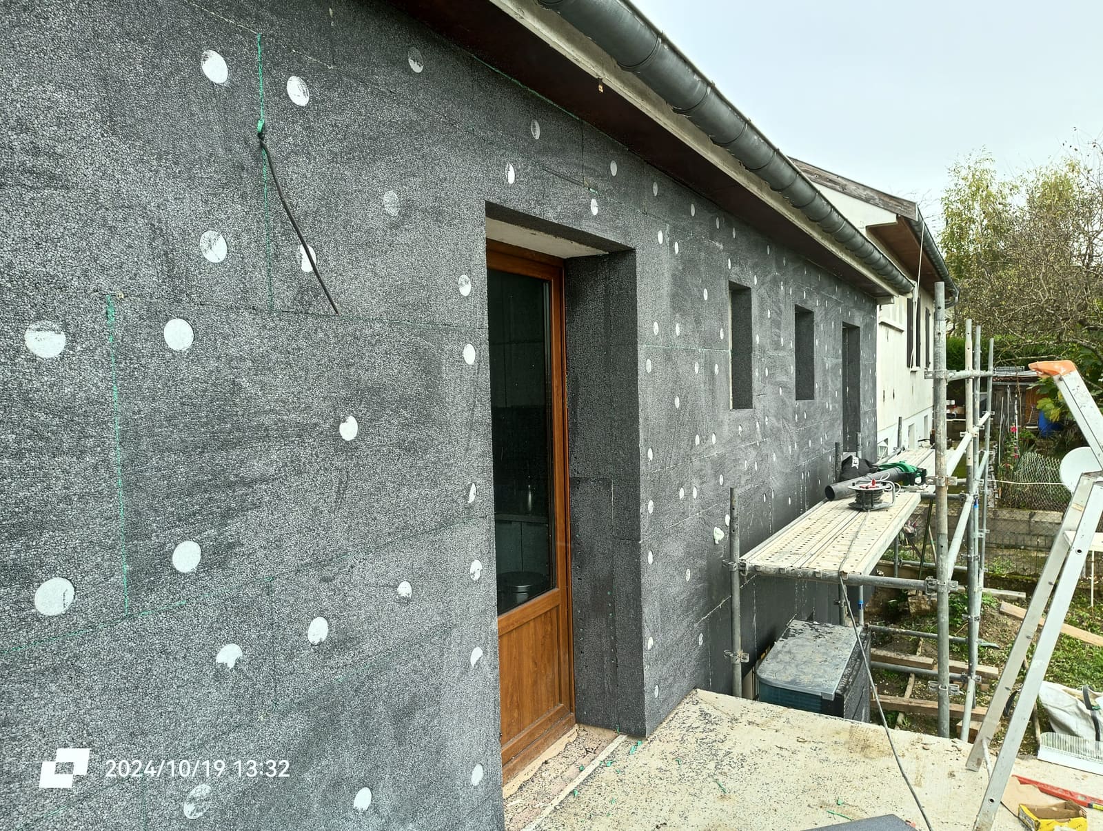 Panneaux isolants fixés par chevilles à rosace sur une façade, pendant la pose d’une isolation par l’extérieur