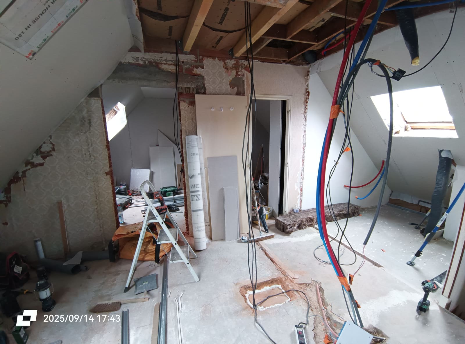 Combles mis à nu pendant la rénovation : cloisons déposées, chevrons apparents et réseaux électriques et sanitaires en attente