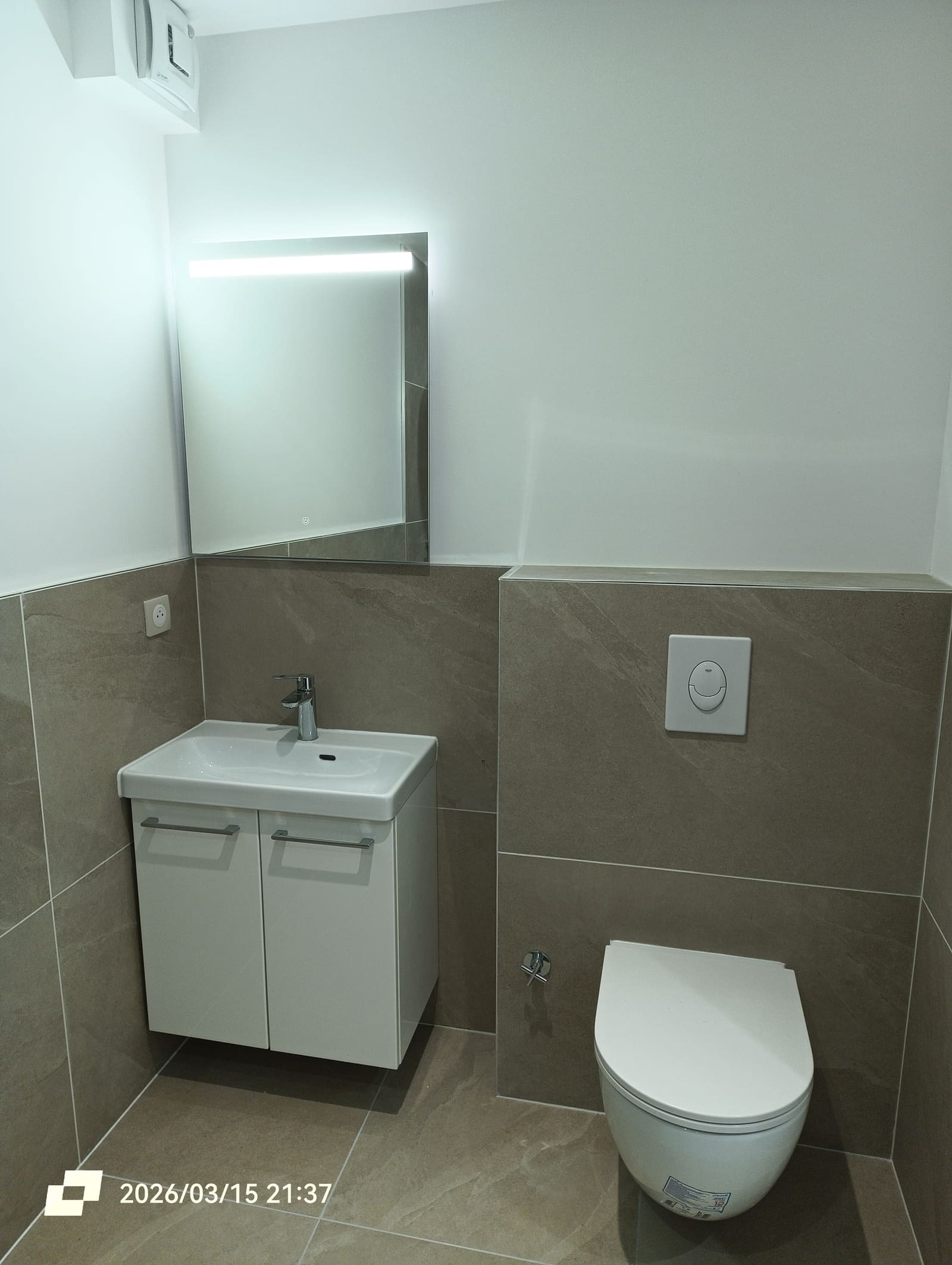 Salle d’eau neuve avec vasque sur meuble, miroir rétroéclairé et WC suspendu sur bâti carrelé