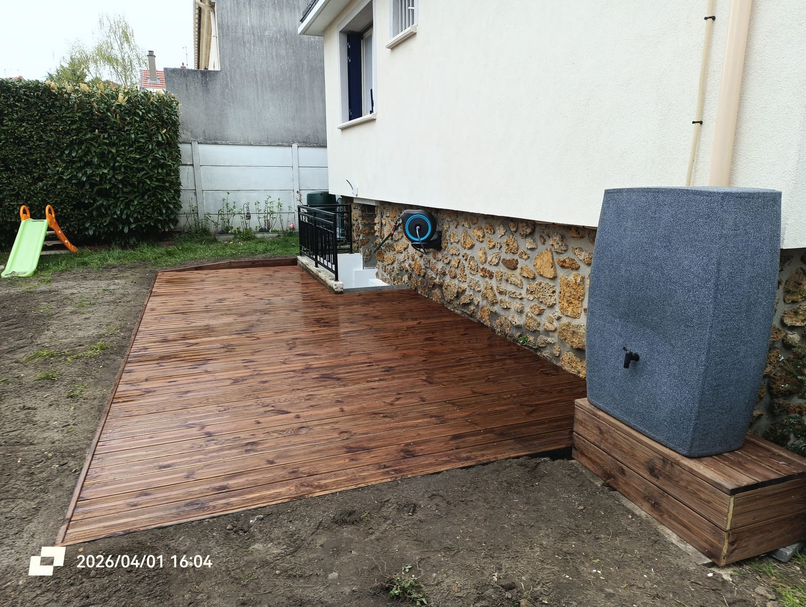 Terrasse en lames de bois terminée le long d’une maison, posée sur la zone terrassée quelques jours plus tôt