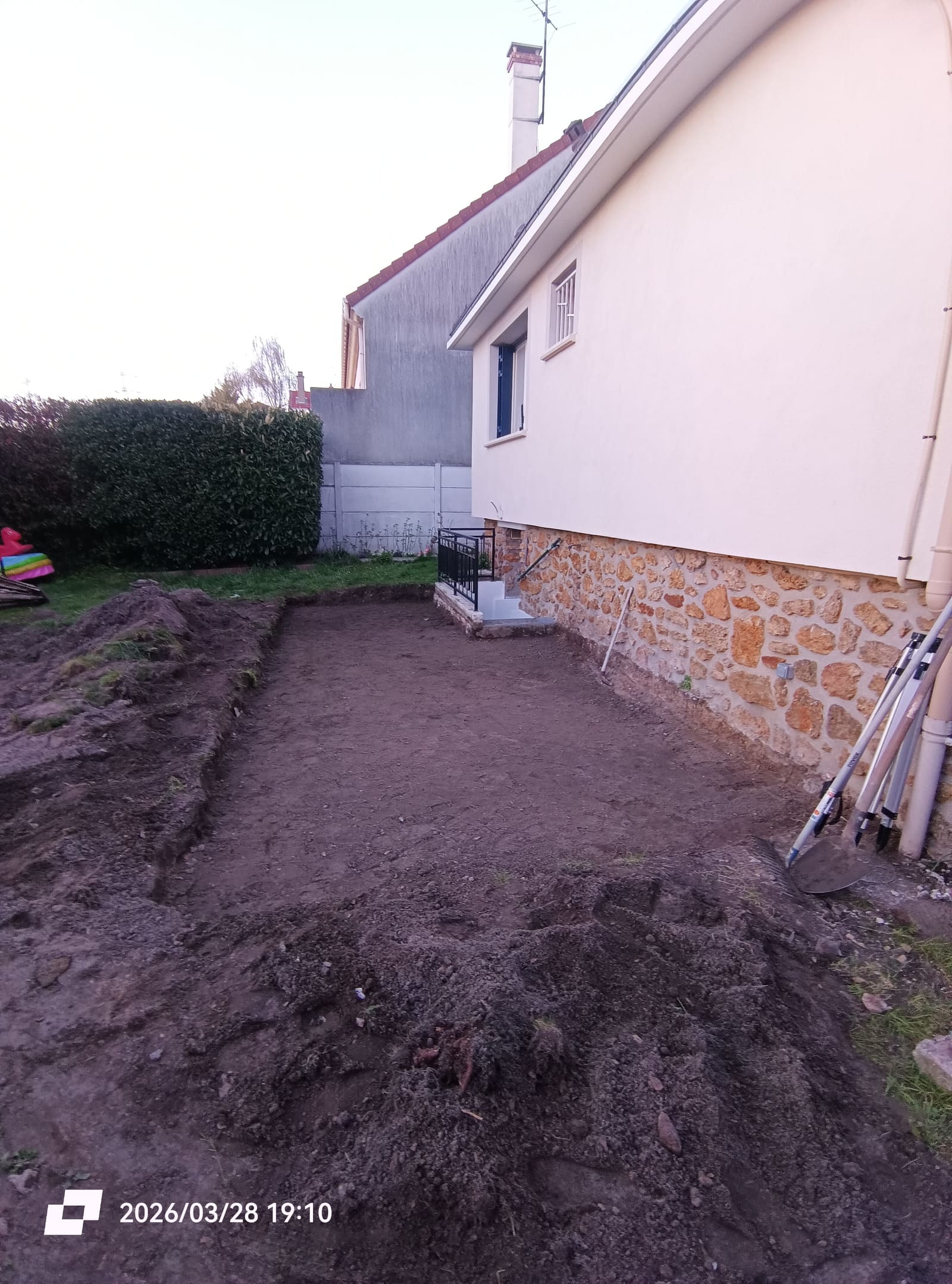 Bande de jardin décaissée et nivelée le long d’une maison, en préparation d’une terrasse en bois